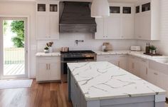 a large kitchen with white cabinets and marble counter tops, along with an island in the middle