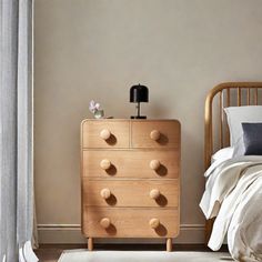 a wooden dresser sitting next to a bed with white sheets and pillows on top of it