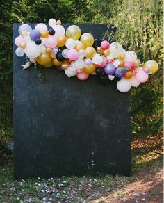 an image of balloons in the air on top of a black box with trees behind it