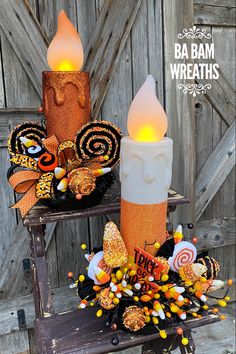 two candles are decorated with candy and candies, one is made out of an orange candle