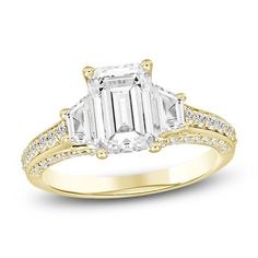 an emerald cut diamond engagement ring set in yellow gold with diamonds around the band and shoulders