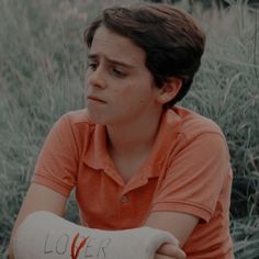 a young man with an arm cast sitting in the grass