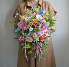 a woman holding a bouquet of flowers in front of her face and wearing a brown shirt