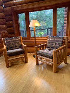 two wooden chairs sitting on top of a hard wood floor in front of a window