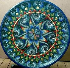 an artistically painted plate sitting on top of a wooden table next to a wall