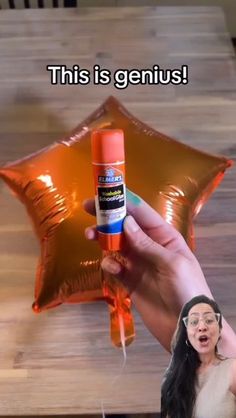 a person holding an orange spray bottle in front of a star shaped balloon with the caption, this is genius