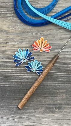 a pair of scissors next to some blue and orange thread on a wooden table with flowers