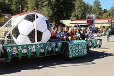 a parade float with a soccer ball on it's back and people watching from the sidelines