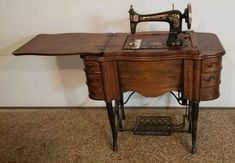 an old sewing machine sitting on top of a wooden table next to a white wall