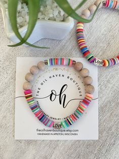 two bracelets with colorful beads on top of a card next to a potted plant