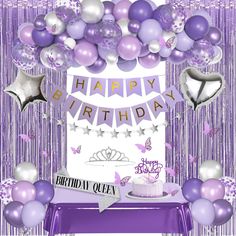 a birthday cake surrounded by balloons and confetti on a purple table clothed backdrop