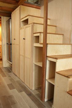 an empty room with wooden shelves and drawers on the wall, next to a stair case