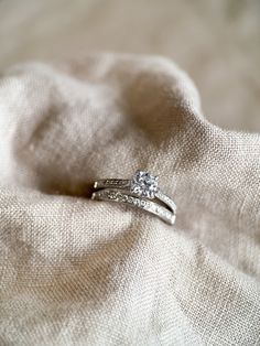 two wedding rings sitting on top of a white cloth