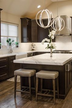 a kitchen island with stools in front of it and an island that has flowers on top