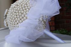 a bridal bouquet with white pearls and tulle on the top, sitting on a table