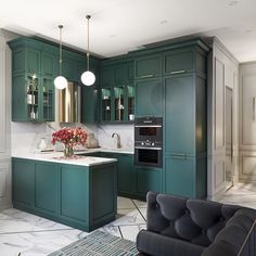 a kitchen with green cabinets and marble counter tops