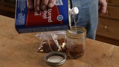 a person pouring something into a jar on top of a wooden table