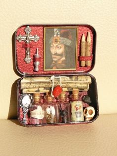 an open suitcase with various items inside on a table next to a painting and coffee mug