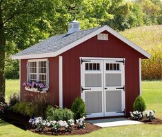 a red and white shed with flowers in the window boxes on the front lawn area