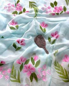 a bird is laying on a white sheet with pink flowers