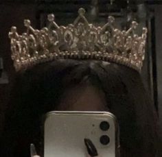 a woman taking a selfie with her cell phone wearing a crown on top of her head