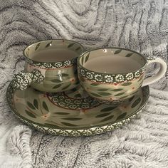 two cups and saucers are sitting on a blanket