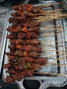 several skewers of meat and vegetables on a metal tray