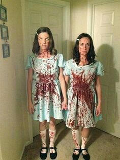 two women dressed as zombies standing in a hallway with one holding the other's hand