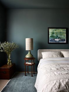 a bedroom with blue walls and white linens on the bed, two nightstands next to each other