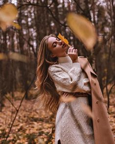 a woman is standing in the woods with her hands on her face and looking up