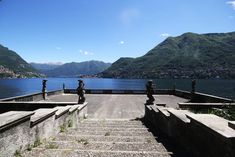 an outdoor area with steps leading to the water and mountains in the backgroud