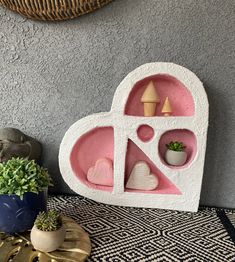 a heart shaped shelf sitting next to a potted plant