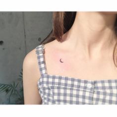 a woman with a half moon tattoo on her chest is wearing a gingham top