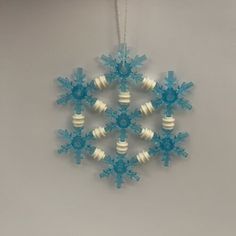 a snowflake ornament hanging from a string on a gray wall with white and blue decorations