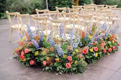 a row of chairs with flowers on the ground next to each other in front of them