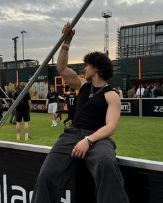 a man sitting on top of a metal pole in front of a crowd at a baseball game