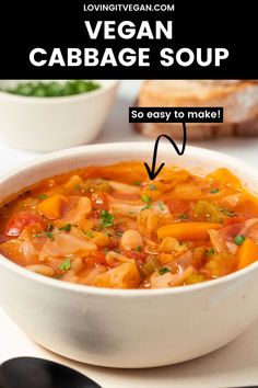 a white bowl filled with vegetable cabbage soup on top of a table next to bread