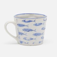 a blue and white coffee cup with fish on the inside, sitting in front of a white background