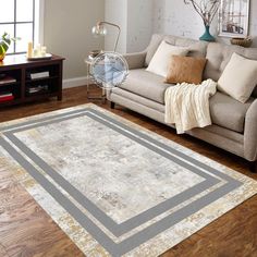 a living room filled with furniture and a rug on top of a hard wood floor