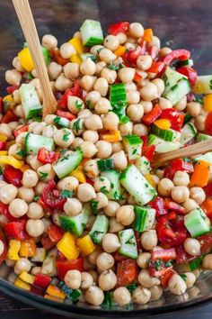 a salad with chickpeas, cucumbers, and tomatoes in a glass bowl