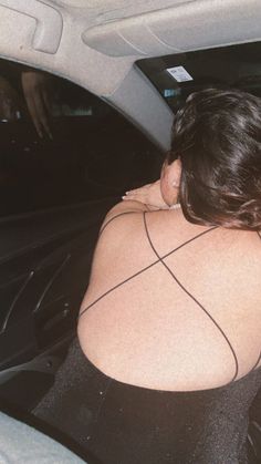 a woman sitting in the back seat of a car with her arm wrapped around another woman's neck