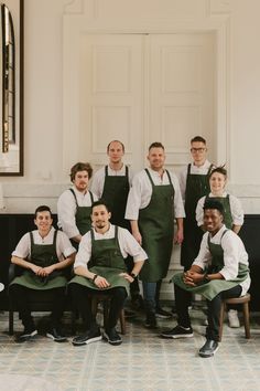 a group of men in green aprons posing for a photo