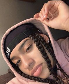 a woman with braids on her head wearing a pink hoodie and looking at the camera