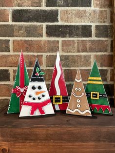 three small christmas trees sitting next to each other on a wooden shelf in front of a brick wall