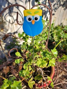 a blue bird with a yellow crown on it's head sitting in a potted plant