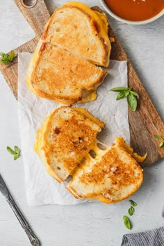 two grilled cheese sandwiches sitting on top of a cutting board