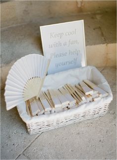 a white basket filled with wooden sticks and a sign that reads keep cool with a fan please help yourself