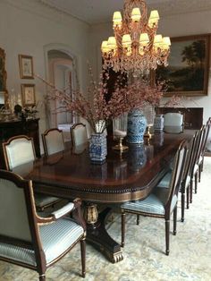 a dining room table with blue vases on it and chandelier hanging from the ceiling