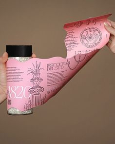 two hands holding a pink package with writing on it and paper in the shape of a bird