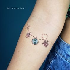 a woman's arm with a tattoo on it that has an earth and luggage attached to it